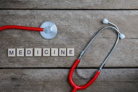 Medicine text word made with wood blocks and Red Heart,stethoscope on wooden table, health background concepts.の写真素材
