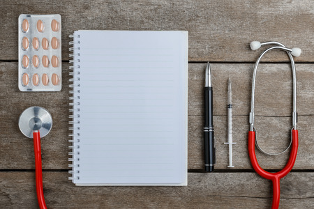 doctor workplace with a stethoscope on wooden table, health background concepts.の写真素材