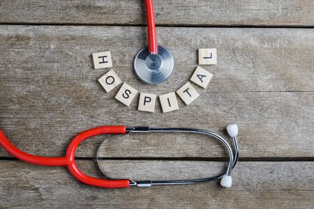 Hospital text word made with wood blocks and Red Heart,stethoscope on wooden table, health background concepts.の写真素材