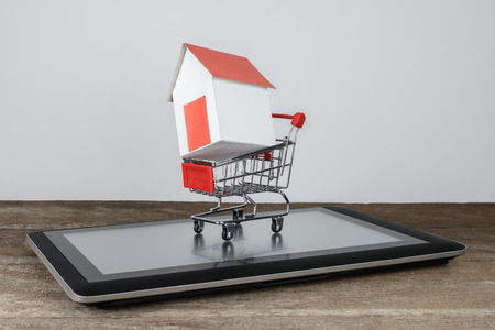 House model in shopping cart on tablet. Trading house online, Selling products online conceptsの写真素材