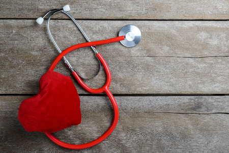 Workplace of a doctor. red heart with a stethoscope on wooden table background, health background concepts.の写真素材