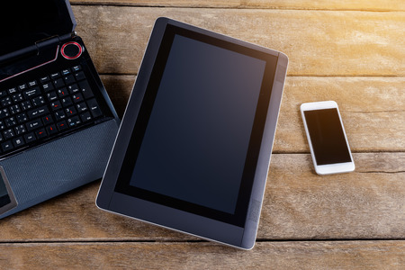 keyboard of Notebook with smartphone and tablet pc on wooden desk