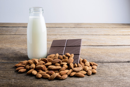 milk in bottle, chocolate and almond on wooden backgroundの写真素材