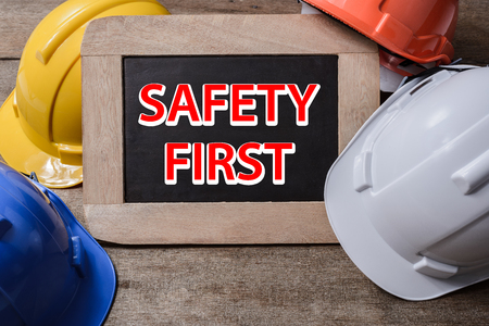 Yellow, Orange, White and Blue protective safety helmet with chalkboard on old wooden background. safety first concepts
