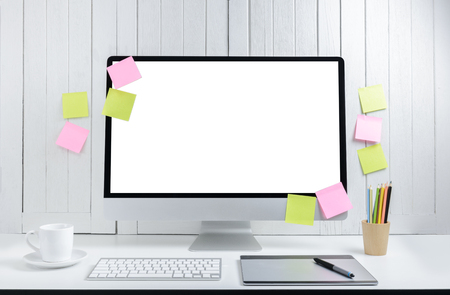 Workplace background for designers with blank white screen modern desktop computer, keyboard, pen mouse, crayon, coffee cup, post-it on a white wooden vintage backgroundの写真素材