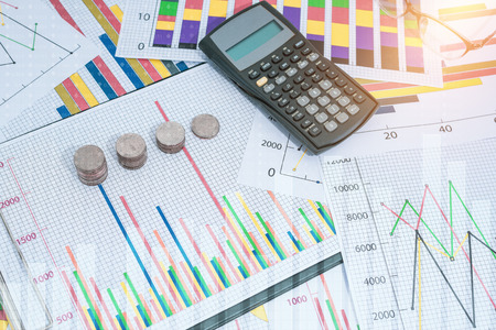 Stack of money coins with calculator, marketing research and business annual report background,...