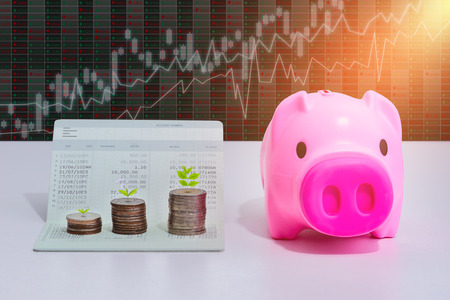 stack of coins with piggy bank and account book bank on the table in saving, banking and finance conceptの写真素材