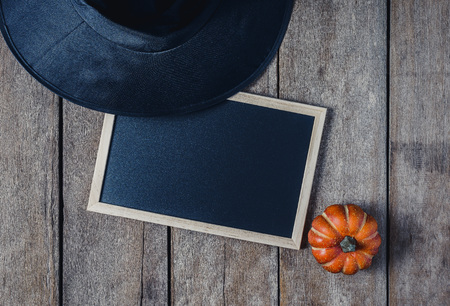 halloween background with Pumpkins, Witch hat and empty chalkboard on wooden floor. view from aboveの写真素材