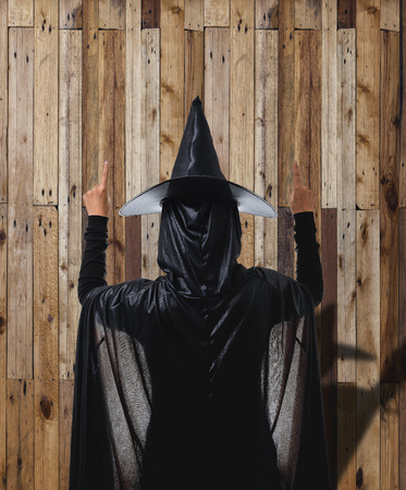Back View Portrait of woman in black Scary witch halloween costume with Wooden Wall Panels is backgroundの写真素材
