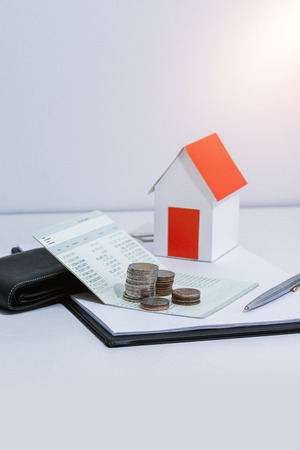 saving account passbook or financial statement, paper house model, and coins with Property Leasing Agreement on office desk table. Business, finance, property ladder or mortgage loan conceptの写真素材