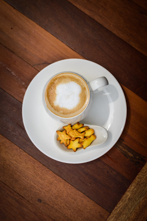 Cup of coffee hot latte on wooden table with little cookie in coffee shop. top view and copy spaceの写真素材