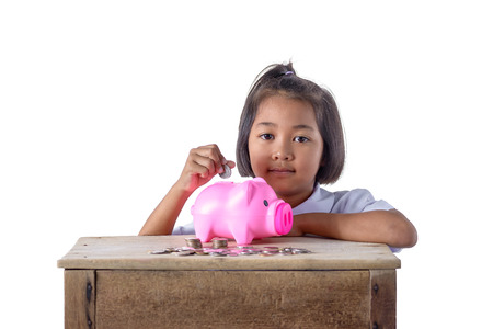 Cute asian girl in school uniform putting coins into piggy bank isolated on white background . Education Savings conceptsの写真素材