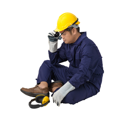 worker in Mechanic Jumpsuit with helmet, earmuffs, Protective gloves and Safety goggles is Sitting isolated on white backgroundの写真素材