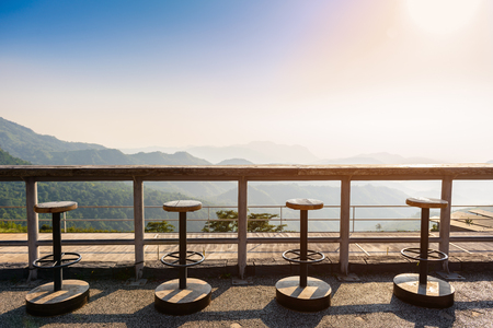 wooden chair stand in a row with counter bar and landscape view of mountain in morningの写真素材