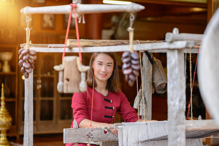 Women in thai dress are weaving with ancient weaving machinesの写真素材