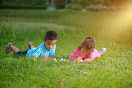 Group of school kids coloring outdoors looking happy in grass of fieldの写真素材
