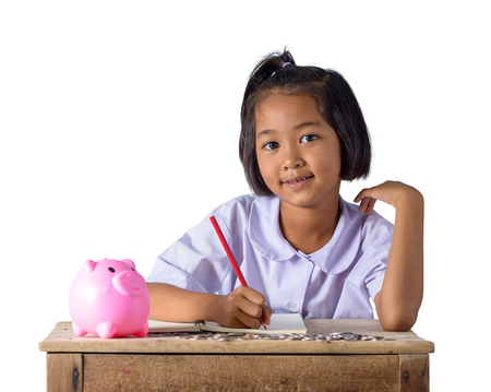 Cute asian country girl in school uniform Make a note of income receipts and coins with piggy bank isolated on white background with clipping path. Education Savings conceptsの写真素材