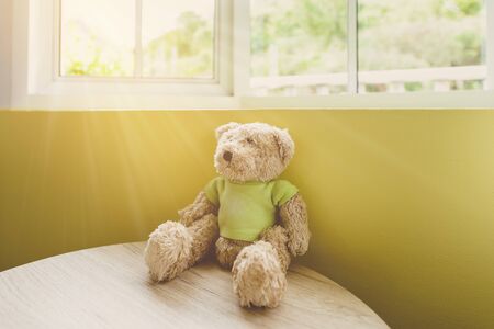 Lonely vintage Teddy bear on a wooden table near the window and light flare. vintage color toneの写真素材