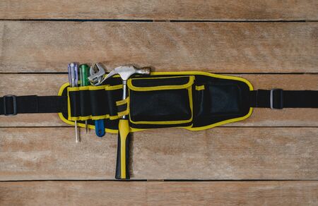 Top view of tool belt bag and old instruments constructor or renovation for build and repair house on rustic grunge wooden backgroundの写真素材