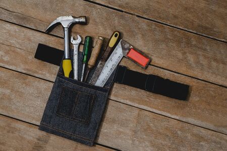 Top view of tool belt bag and old instruments constructor or renovation for build and repair house on rustic grunge wooden backgroundの写真素材