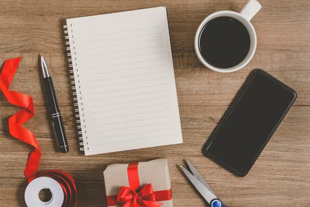 New Year's Resolutions List written on Notebook with gift box and smart phone, pen, coffee on wooden backgroundの写真素材