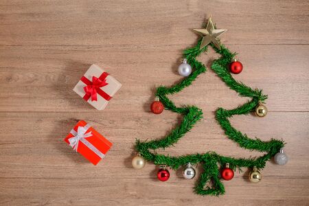 Creative winter layout made with evergreen tree branches and ornament, gift boxes on wooden background. Flat lay Christmas trees concepts. Top view and copy spaceの写真素材