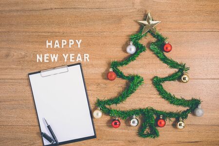 Creative winter layout made with evergreen tree branches and ornament, empty clipboard on wooden background. Flat lay Christmas trees and New Year concepts. Top view and copy spaceの写真素材