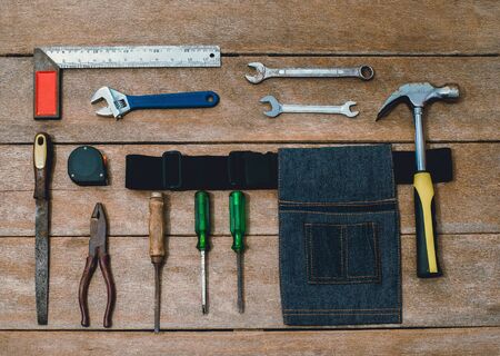 Top view of tool belt bag and old instruments constructor or renovation for build and repair house on rustic grunge wooden backgroundの写真素材