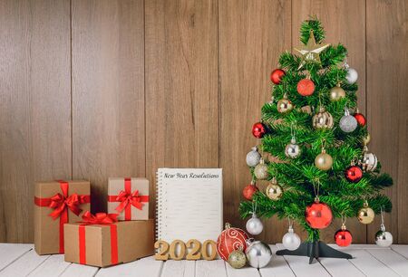christmas tree with colorful balls ornaments and gift boxes with 2020 wooden text and New Year's Resolutions List written on Notebook with copy spaceの写真素材