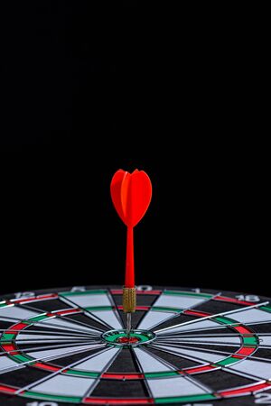 Red dart arrow hitting in the target center Dart board on Black background, Setting aim goal achievement concept challenging business goals And ready to achieve the goal and Marketing conceptの写真素材