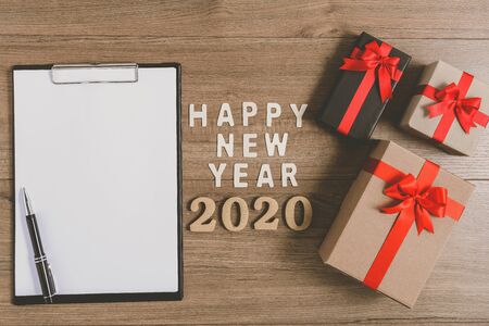 HAPPY NEW YEAR 2020 Wood New Year's Resolutions List written on clipboard with gift box on wooden backgroundの写真素材
