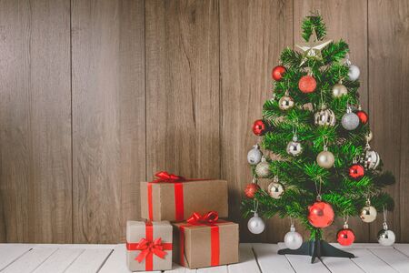 christmas tree with colorful balls ornaments and gift boxes on wooden background with copy spaceの写真素材