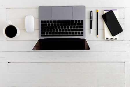 Flat lay, top view wooden office desk. Workspace with blank notebook, laptop, mouse computer, smartphone, pen, coffee cup office supplies with coppy space on white wood table backgroundの写真素材