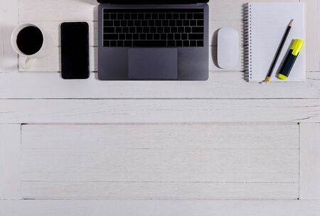 Flat lay, top view wooden office desk. Workspace with blank notebook, keyboard, mouse computer, laptop, smartphone, pencil, coffee cup office supplies with coppy space on white wood table backgroundの写真素材