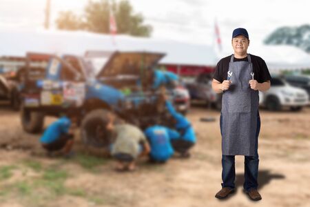 Male Auto mechanic hand holding wrench or Engine repair tools and Blured background of racing Four wheel drive vehiclesの写真素材