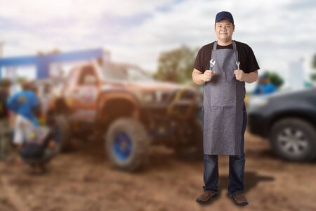 Male Auto mechanic hand holding wrench or Engine repair tools and Blured background of racing Four wheel drive vehiclesの写真素材