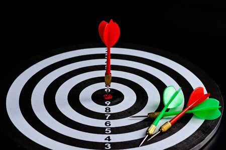 Red and green dart arrow hitting target center Dart board Isolated on black background, Setting aim...
