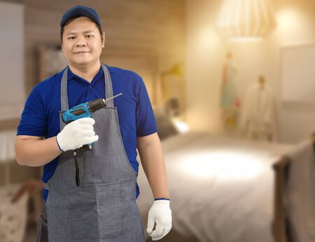 Craftsman home renovation holding electric drill and blurred background of bed roomの写真素材