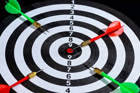 Red and green dart arrow hitting target center Dart board Isolated on black background, Setting aim goal achievement concept challenging business goals And ready to achieve goal and Marketing conceptの写真素材