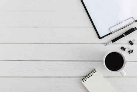 Flat lay, top view wooden office desk. Workspace with blank notebook, pen, metal clip, coffee cup office supplies with coppy space on white wood table backgroundの写真素材