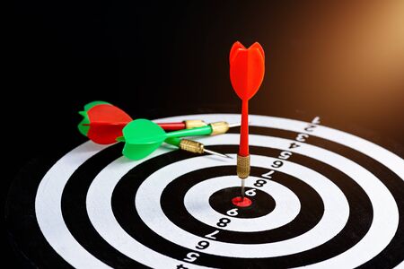 Red and green dart arrow hitting target center Dart board Isolated on black background, Setting aim goal achievement concept challenging business goals And ready to achieve goal and Marketing conceptの写真素材