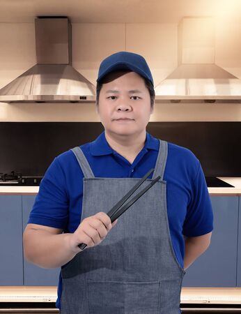 Male Chef assistant holding Kitchen equipment tools and blurred background kitchenの写真素材