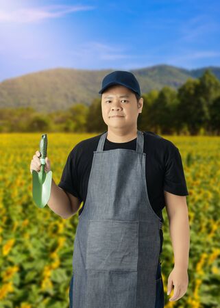 Male gardener hand holding shovel or garden tools and blurred background is flower gardenの写真素材
