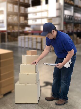 Male staff and parcel boxes checking stock or Preparing Goods For Dispatch and Blurred the background of the warehouseの写真素材