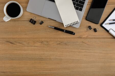 Flat lay, top view wooden office desk. Workspace with blank clipboard, laptop, smartphone, pen, metal clip, coffee cup office supplies with coppy space on wood table backgroundの写真素材
