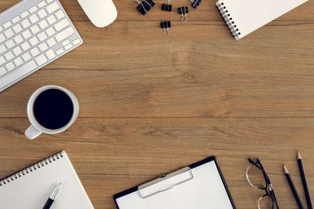 Flat lay, top view wooden office desk. Workspace with blank notebook, keyboard, mouse computer, eye glasses, pen, coffee cup office supplies with coppy space on wood table backgroundの写真素材