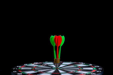 Red and green dart arrow hitting target center Dart board Isolated on black background, Setting aim goal achievement concept challenging business goals And ready to achieve goal and Marketing conceptの写真素材