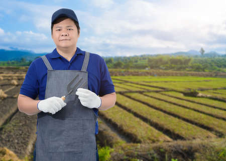Male gardener hand holding shovel or garden tools and blurred background is vegetable gardenの写真素材