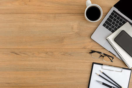 Flat lay, top view wooden office desk. Workspace with blank clipboard, laptop, smartphone, pen, coffee cup office supplies with coppy space on wood table backgroundの写真素材