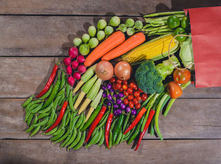 Backgroud of fresh food tasty and healthy many vegetables come out of paper shopping bag on the wooden table. Concept of buying vegetables for healthの写真素材